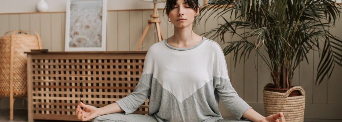 Woman meditating in lotus pose indoors, embracing relaxation and tranquility.