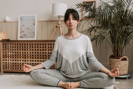 Woman meditating in lotus pose indoors, embracing relaxation and tranquility.